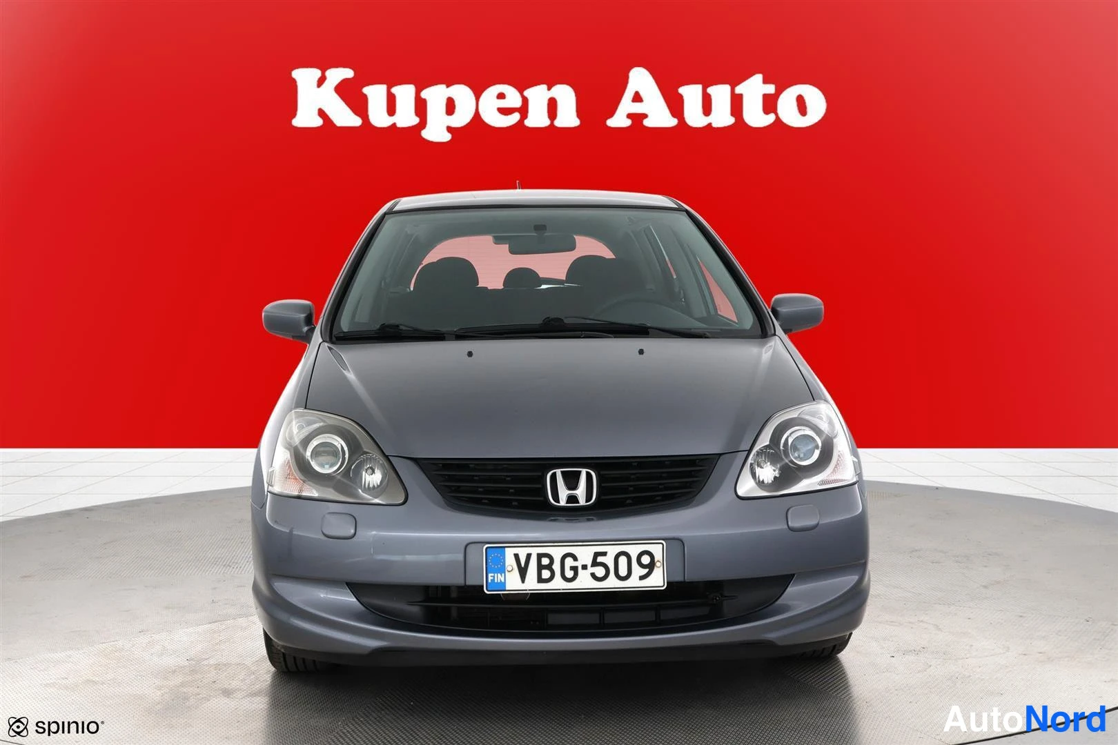 Edestä: Hopeanharmaan Honda Civic -viistoperän keula suoraan edestä, rekisteritunnus, punainen tausta.