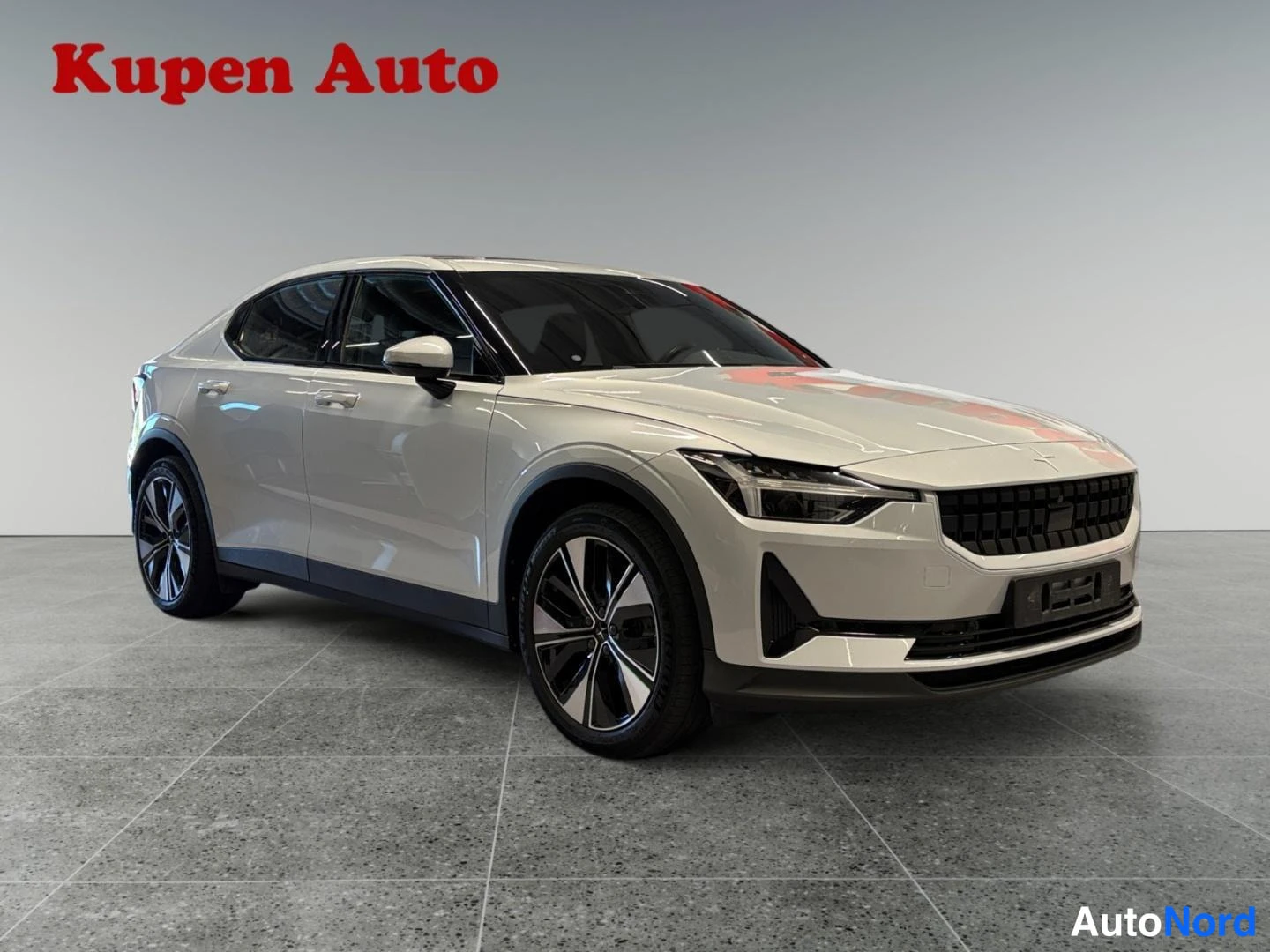 Etuviisto, nokka oikealle: Valkoinen Polestar 2 - henkilöauto kuvattu vinosta edustakulmasta.