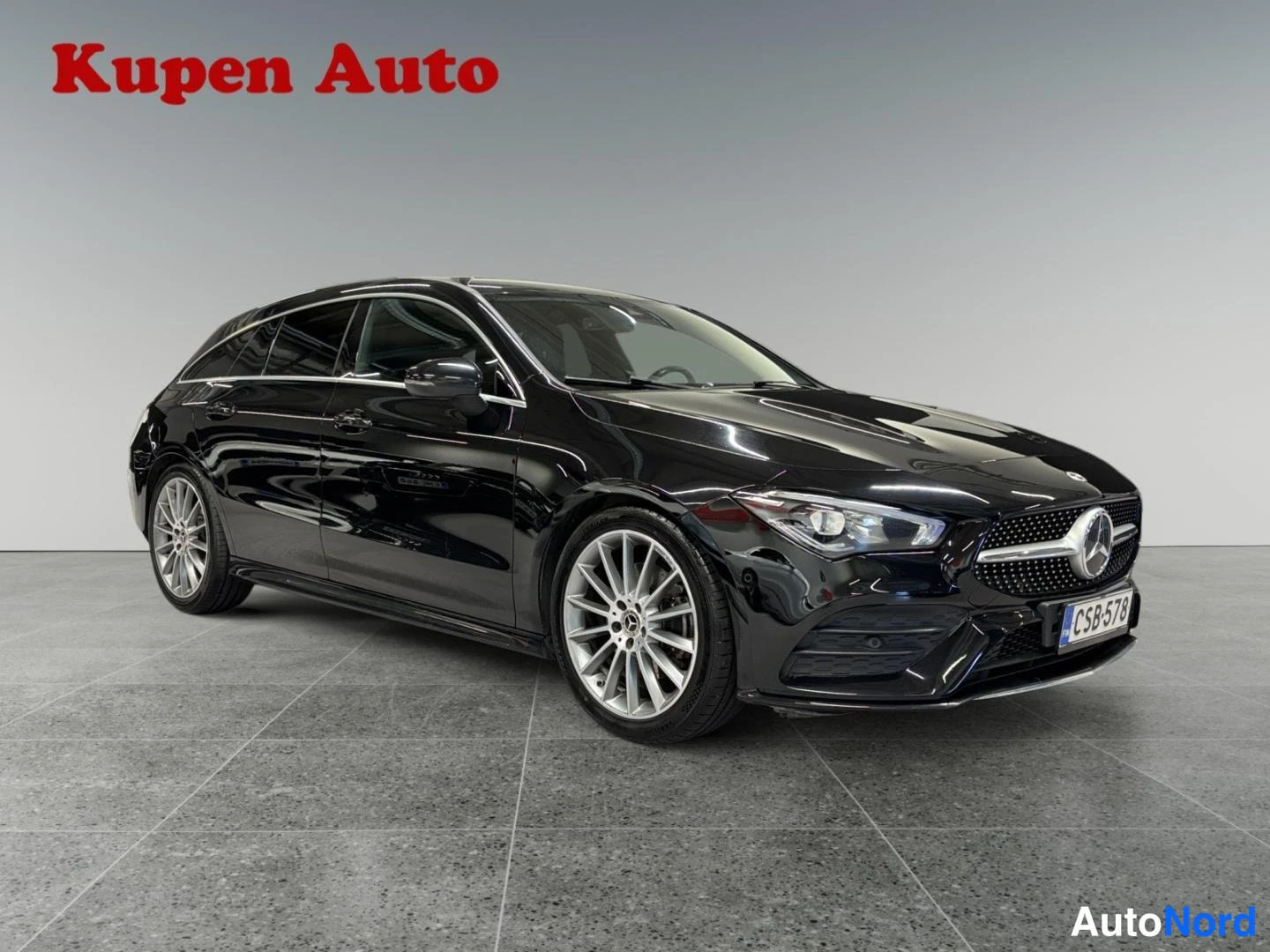 Etuviisto, nokka oikealle: Musta Mercedes-Benz CLA Shooting Brake etuoikeasta kolmannesta, Kupen Auton tiloissa.