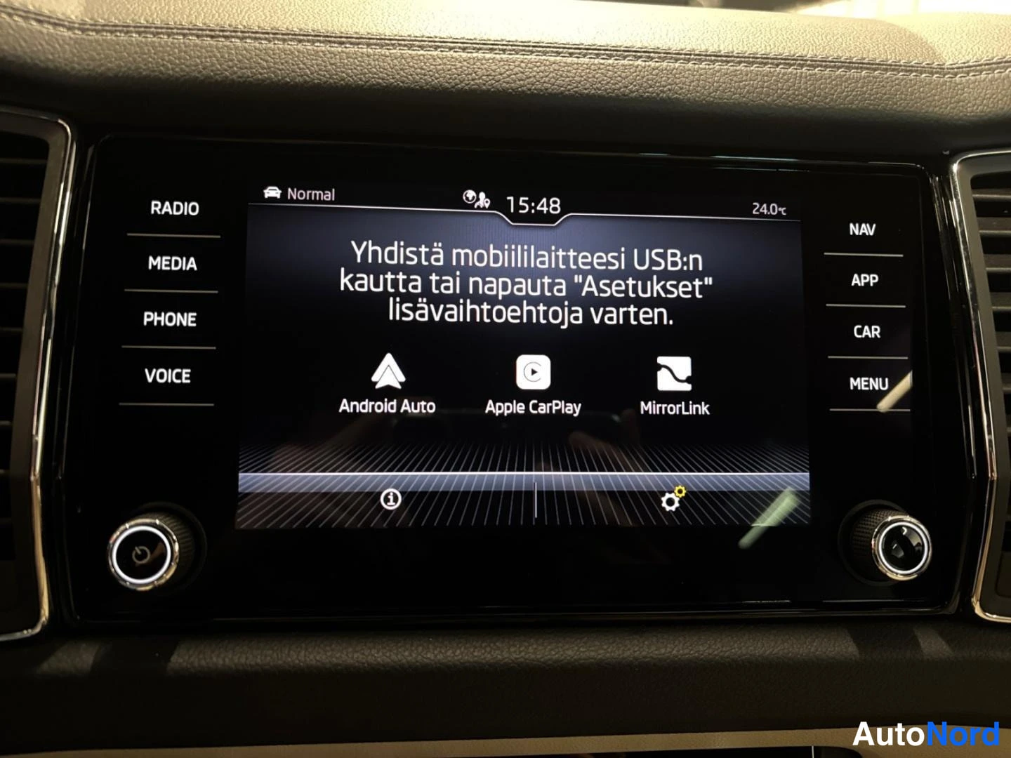 Yksityiskohta: KojelautaanMedianäyttö, jossa valittavissa Android Auto, Apple CarPlay ja MirrorLink; sivupainikkeet RADIO, MEDIA, PHONE, VOICE, NAV, APP, CAR, MENU.