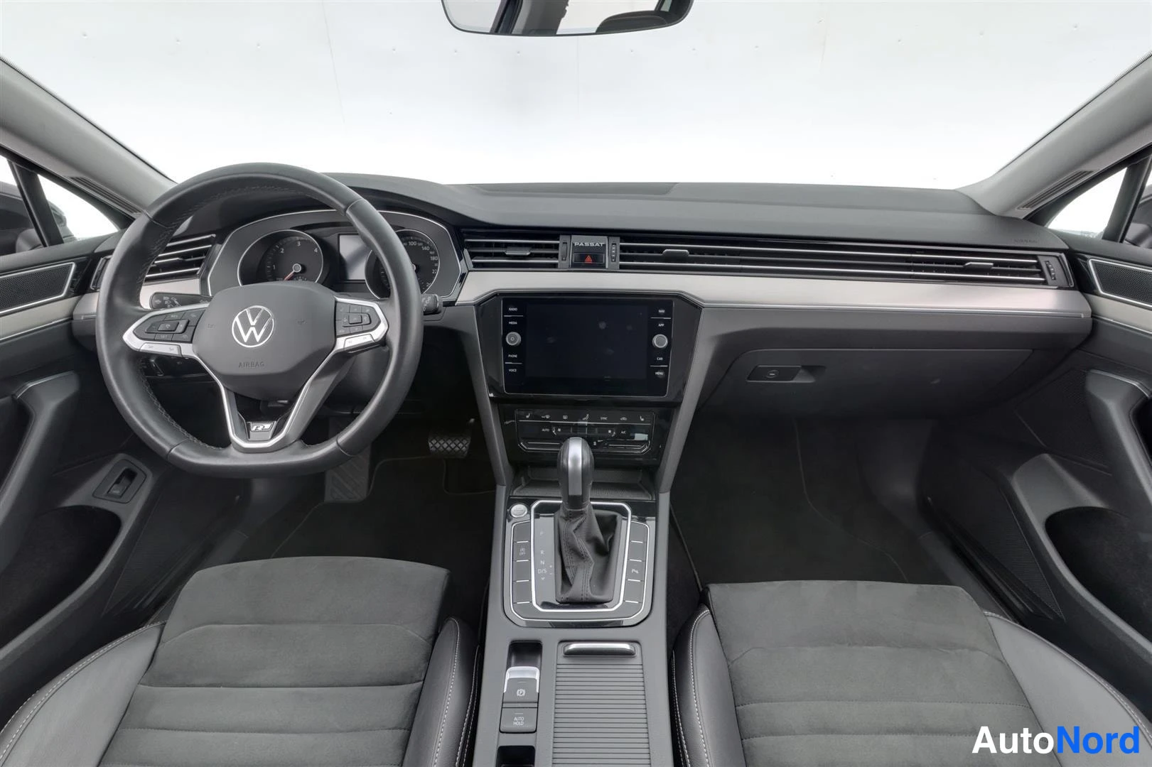 Muu: Auton sisätilat etualalta: Volkswagen-ohjauspyörä, analogiset mittarit, kosketusnäyttö keskikonsolissa, automaattivaihteen valitsin ja kaksi tummaa etuistuintä.