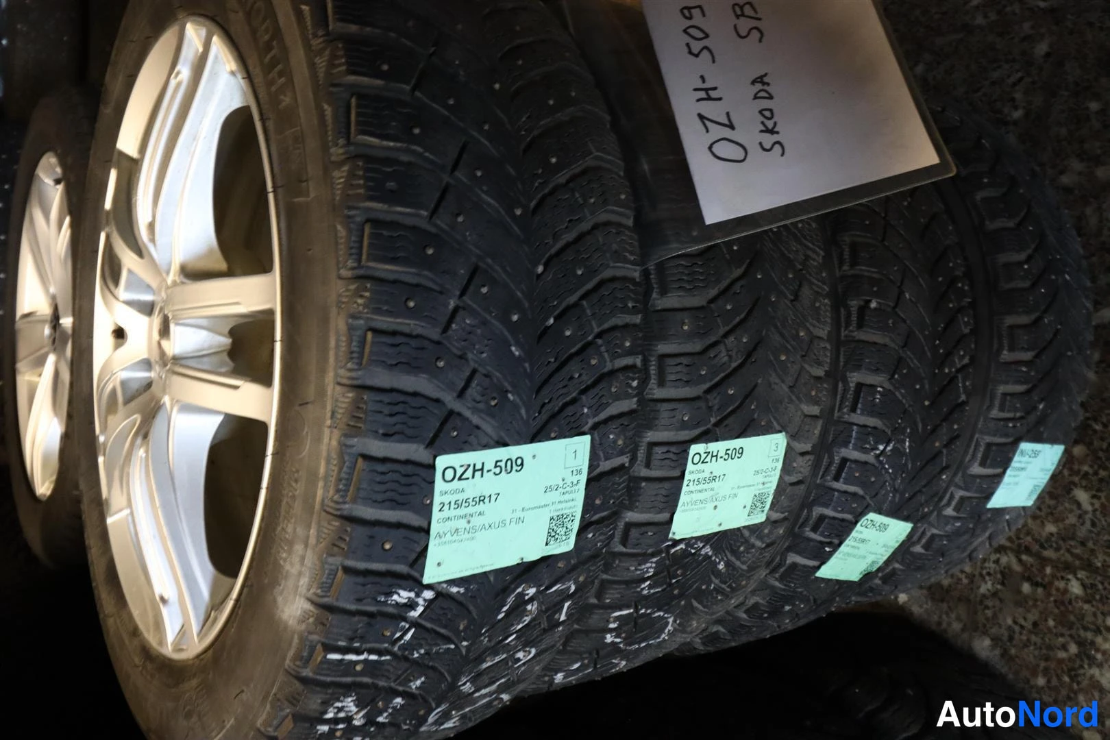 Yksityiskohta: Kärrynläjä nastarenkaita alumiinivanteilla, tarroissa, 215/55R17, SKODA SB.