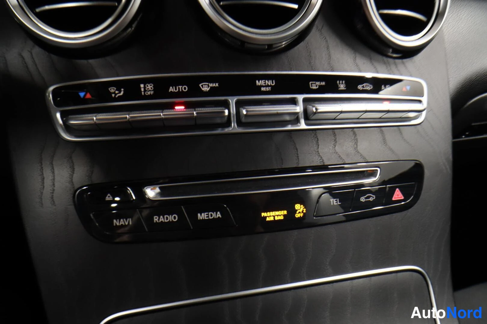 Muu: Auton kojelaudan ilmastointilaitteen painikkeet: AUTO, MAX, MENU REST, DEFROST ja lämmitysmerkit, alla NAVI-, RADIO-, MEDIA- ja TEL-painikkeet sekä PASSENGER AI