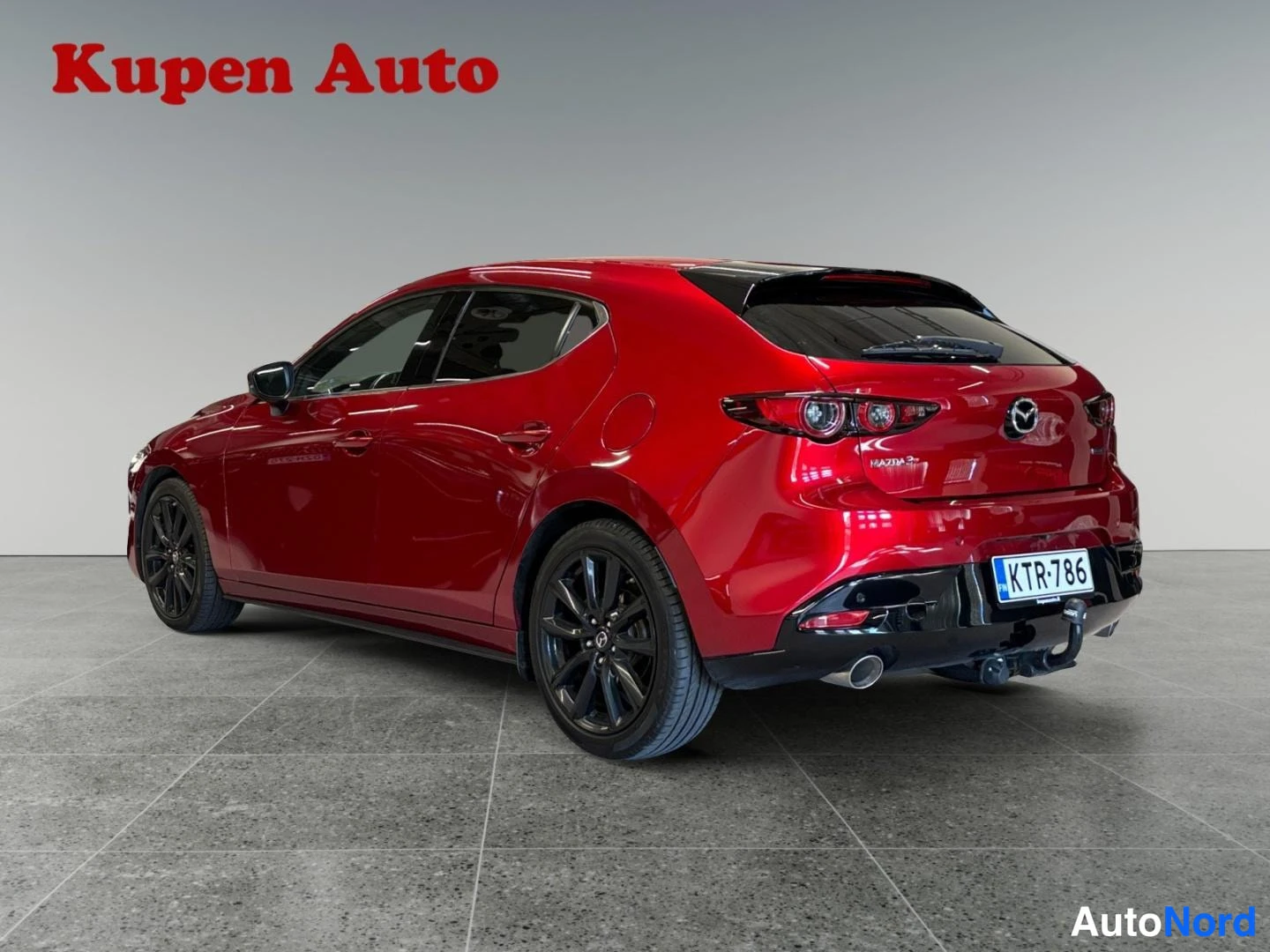 Takaviisto: Punaisen Mazda 3:n takaosa ja oikea kylki, rekisteritunnus, jäätävänviljassa tummat vanteet.