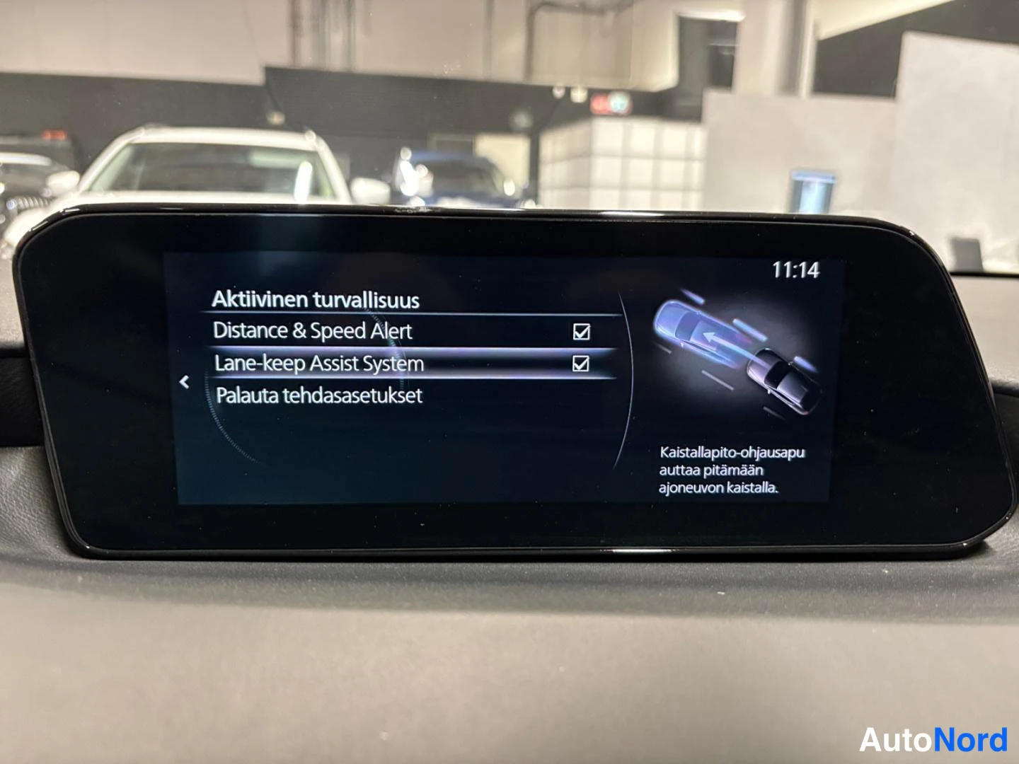 Yksityiskohta: Auton kojelaudan näyttö, jossa on aktiivisen turvallisuuden valikko: Distance & Speed Alert ja Lane-keep Assist System valittuina.