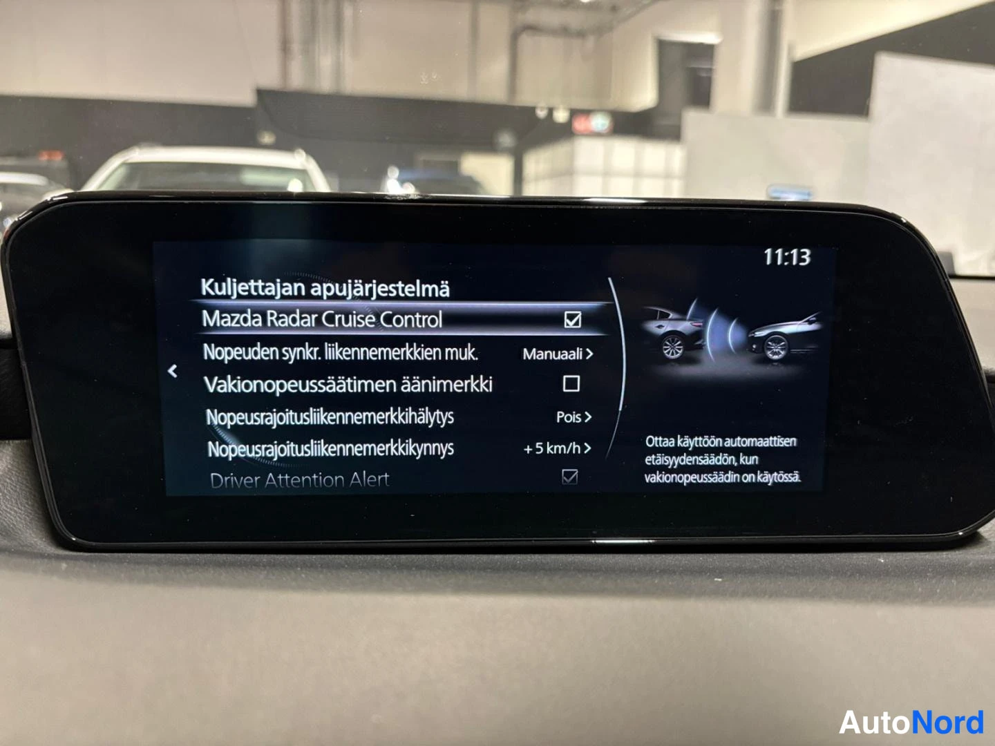 Yksityiskohta: Auton kojelaudan näyttö, jossa on kuljettajan apujärjestelmien valikko: Mazda Radar Cruise Control valittuna.