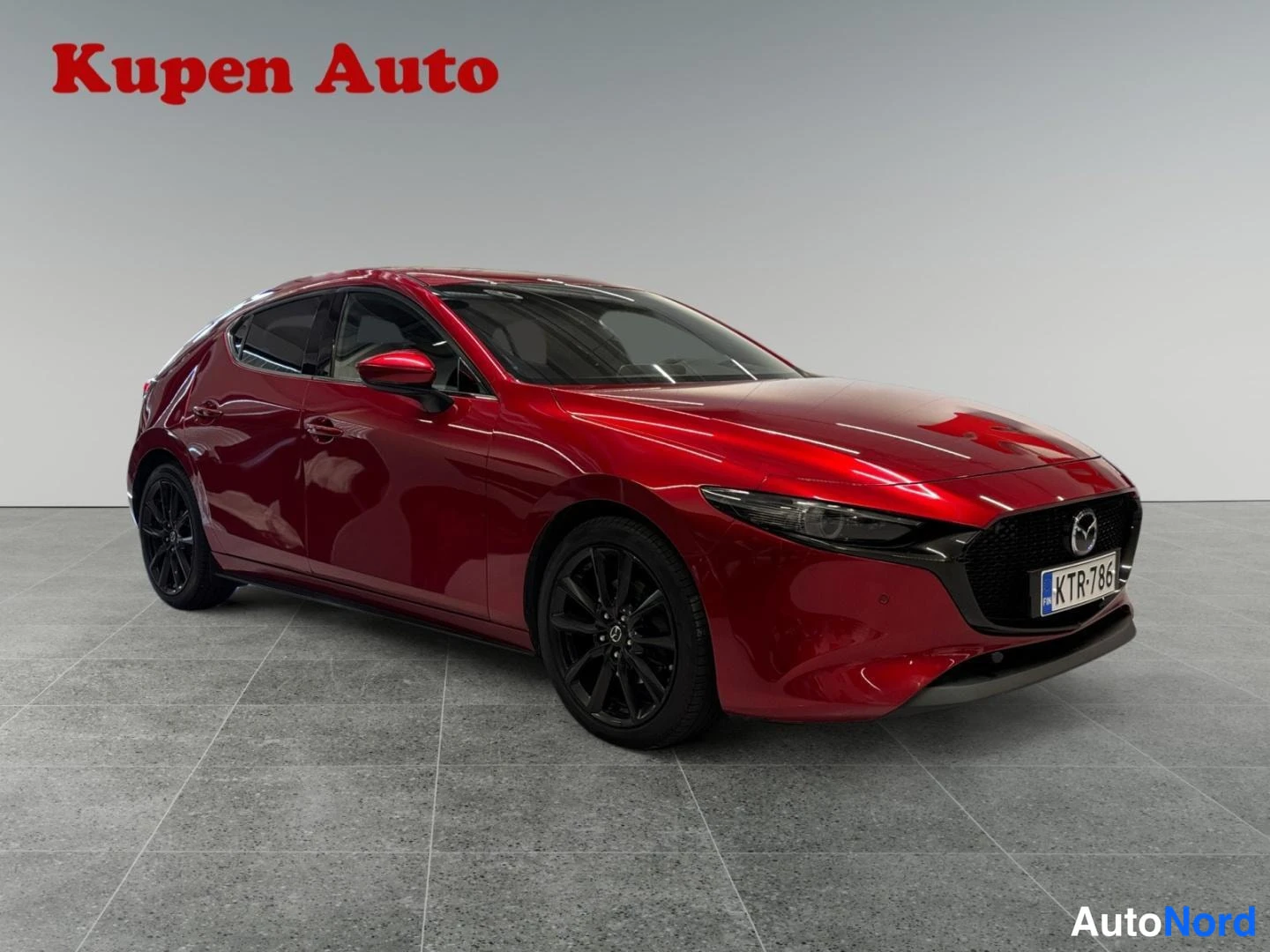 Etuviisto, nokka oikealle: Punaisen Mazda 3:n etukulma oikealta, rekisteritunnus.