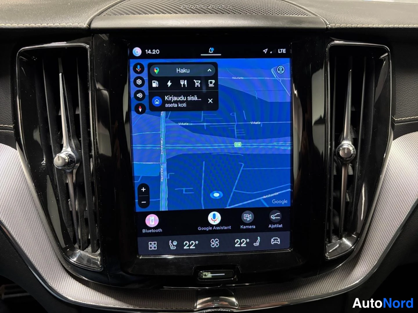 Yksityiskohta: Kojelaudan keskellä oleva pystysuora infotainment-näyttö, jossa näkyy Google-karttanavigaatio hakuikkunoineen, Bluetooth-, Google Assistant-, Kamera- ja Ajotila