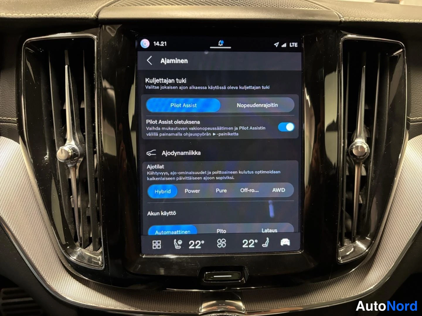 Yksityiskohta: Keskikonsolin näyttö Ajaminen-valikossa: Pilot Assist ja Nopeudenrajoitin -valinta, Ajotilat (Hybrid, Power, Pure, Off-ro…, AWD) sekä Akun käyttö -asetukset.