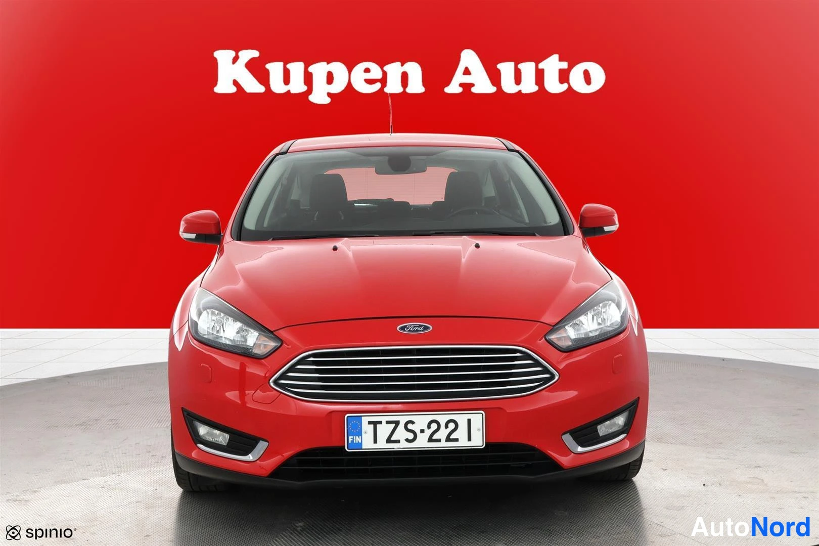 Edestä: Punaisen henkilöauton etupää suoraan edestä, Ford-merkki konepellissä ja rekisterikilpi.
