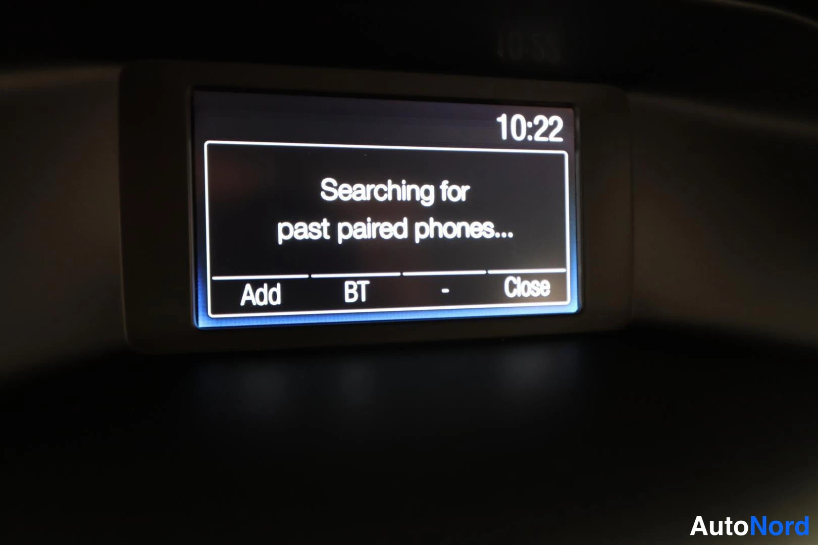 Yksityiskohta: Auton näyttö ilmoittaa 'Searching for past paired phones...' kello 10:22, alavalikot Add, BT, Close.