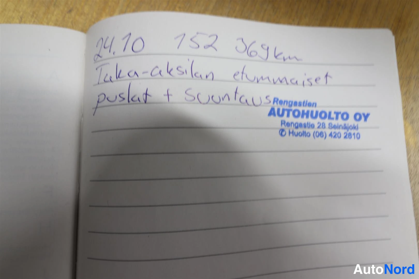 Asiakirja: Huoltokirjan käsin kirjoitettu merkintä 24.10.: taka-akselin etummaiset pusat ja suuntaus, mittarilukema 152 369 km, Autohuolto Oy:n leima.