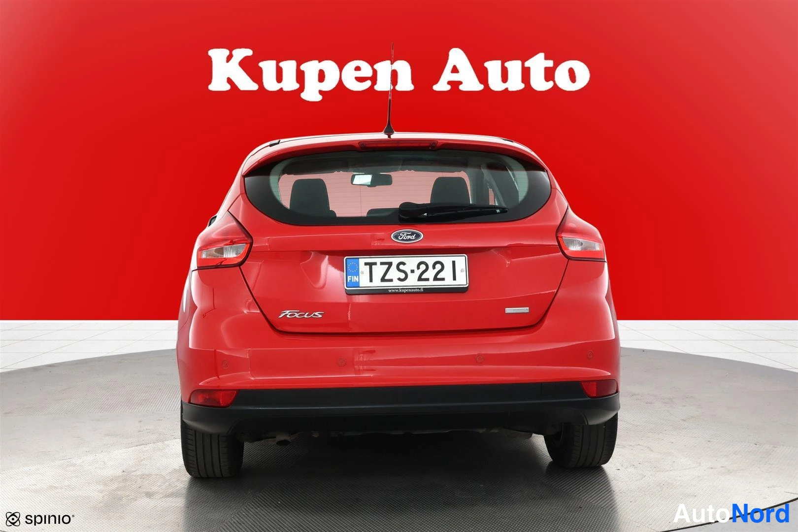 Takaa: Punaisen Ford Focusin takanäkymä, rekisterikilpi, punainen tausta.
