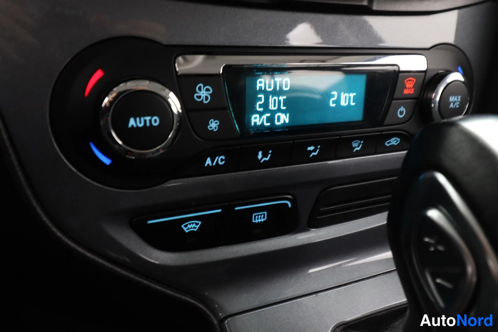 Yksityiskohta: Lähikuva auton kojelaudan ilmastointipaneelista, jossa näkyy AUTO-nappi, A/C-nappi ja näyttö, jolla lukee AUTO, 21°C, 21°C ja A/C ON.