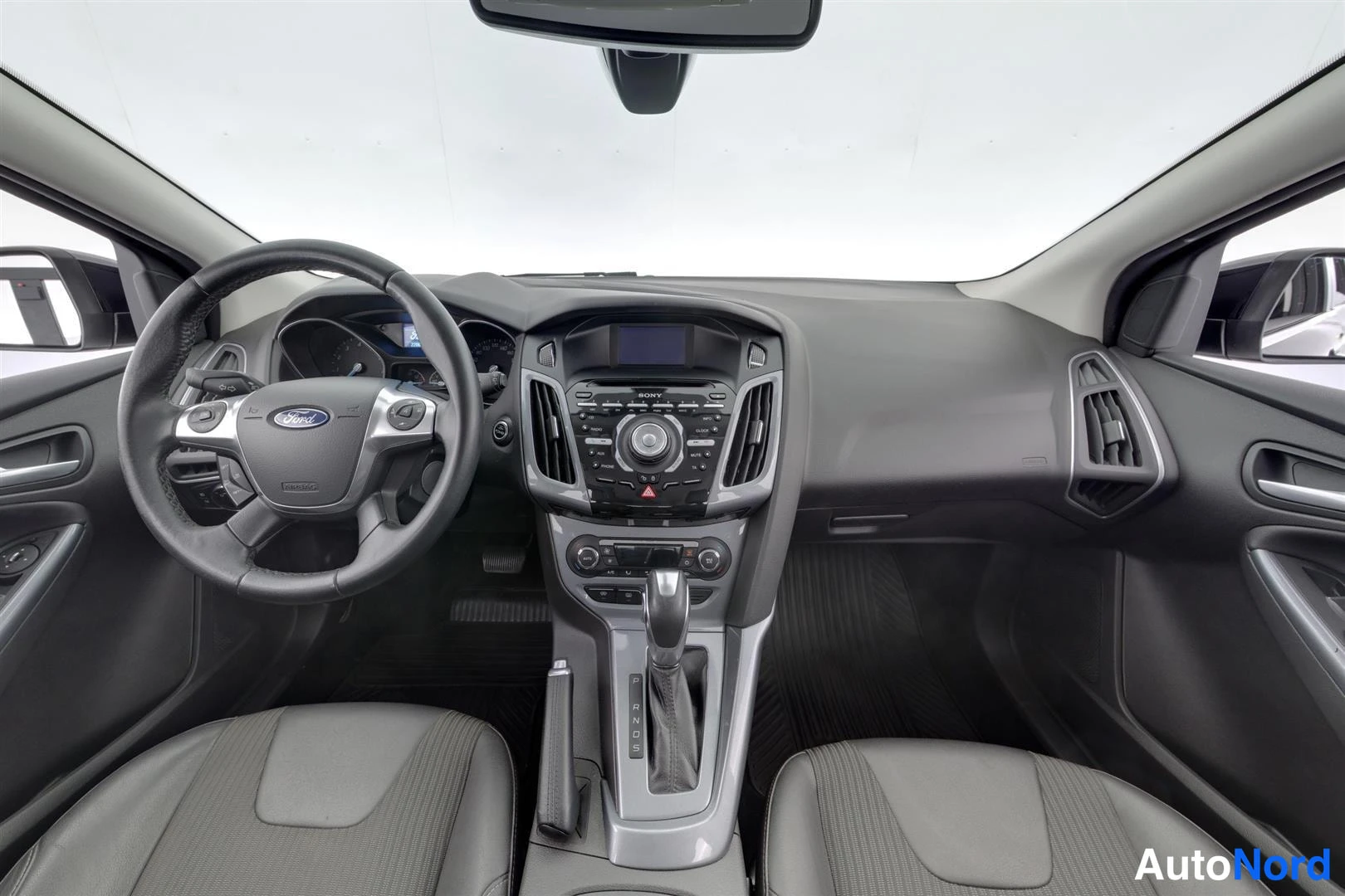 Muu: Ford Focusin ohjaamo edestä kuvattuna: ohjauspyörä vasemmalla, SONY-radio ja automaattivaihteen valitsin keskikonsolissa, kaksi etuistuinta.