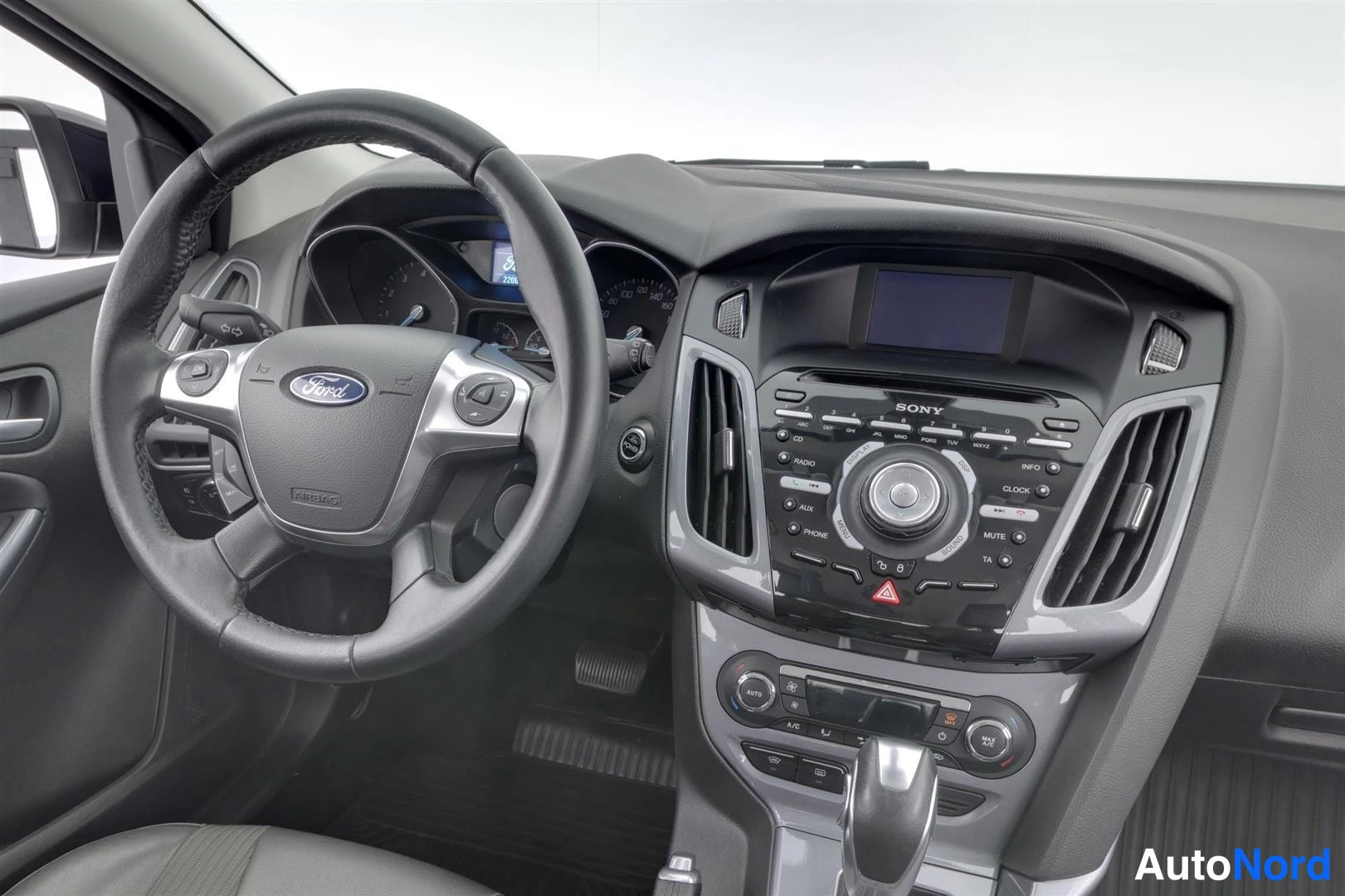 Muu: Lähikuva Ford Focusin kojelaudasta ja ohjauspyörästä, SONY-radiokeskus ja automaattivaihteen valitsin näkyvissä.