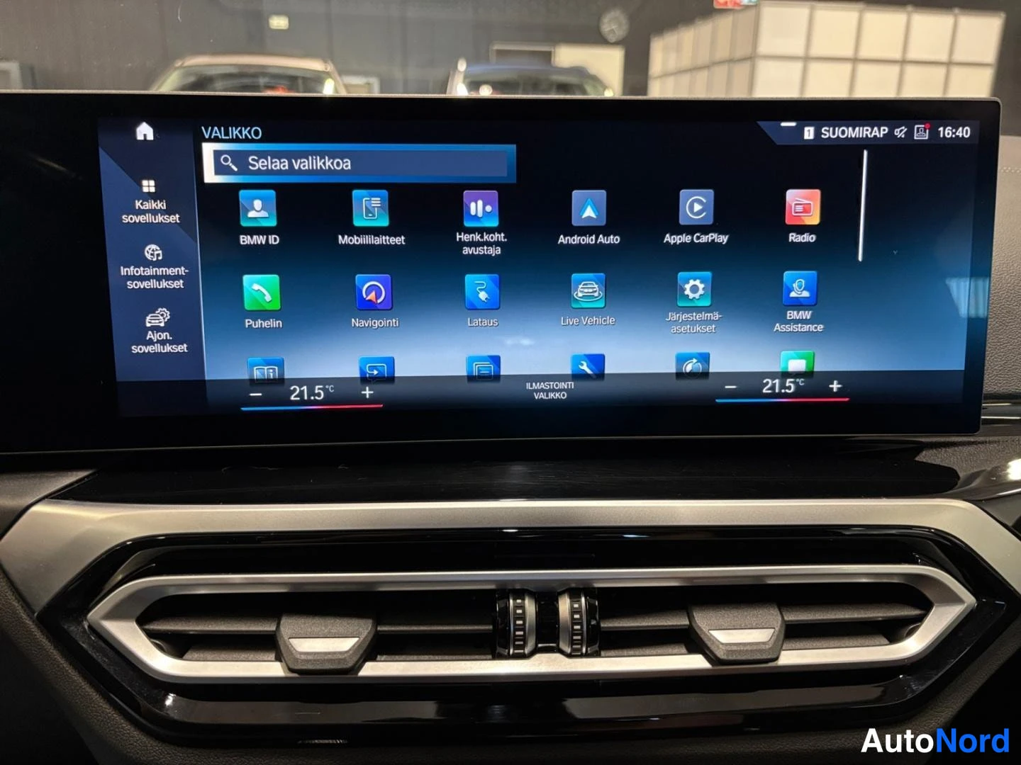 Muu: Keskinäytöksen valikko kuvakkeineen: BMW ID, Mobiililaitteet, Android Auto, Apple CarPlay, Radio, Puhelin, Navigointi, Lataus, Live Vehicle, Järjestelmäasetukse