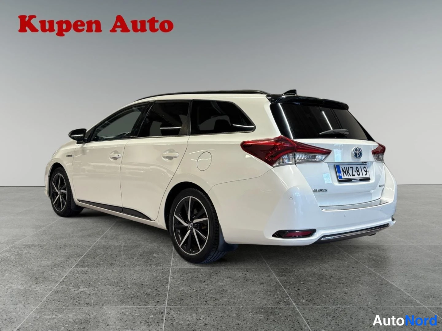 Takaviisto: Toyota Auris Touring Sports -farmarin takakulma vaalean kermanvalkoisella korilla, punaiset takavalot ja -rekisterikilpi.
