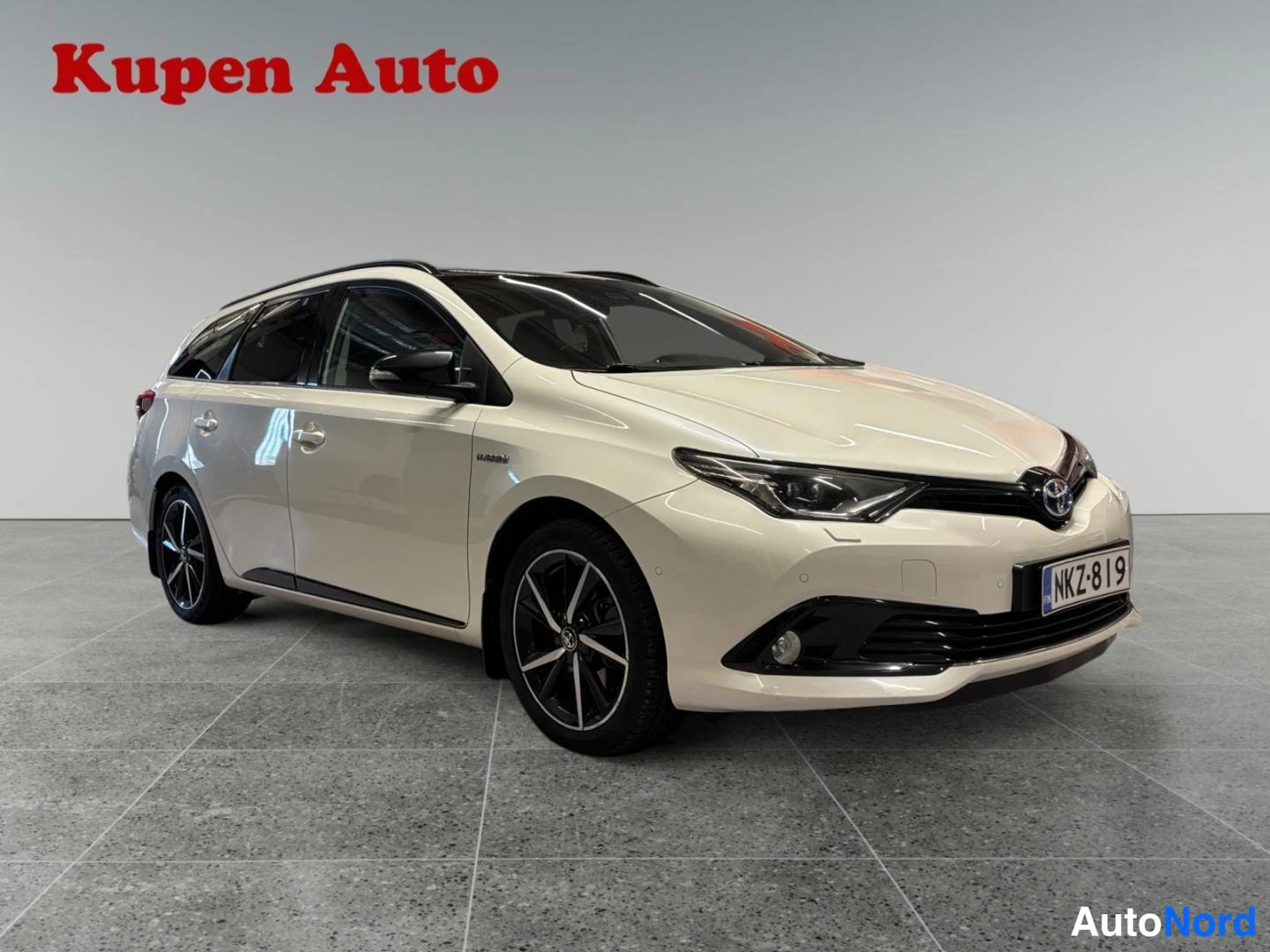 Etuviisto, nokka oikealle: Toyota Auris Touring Sports -farmariauto kuvattuna vinosti edestä oikealta,vaalea kermanvalkoinen koriväri ja tummat vanteet.