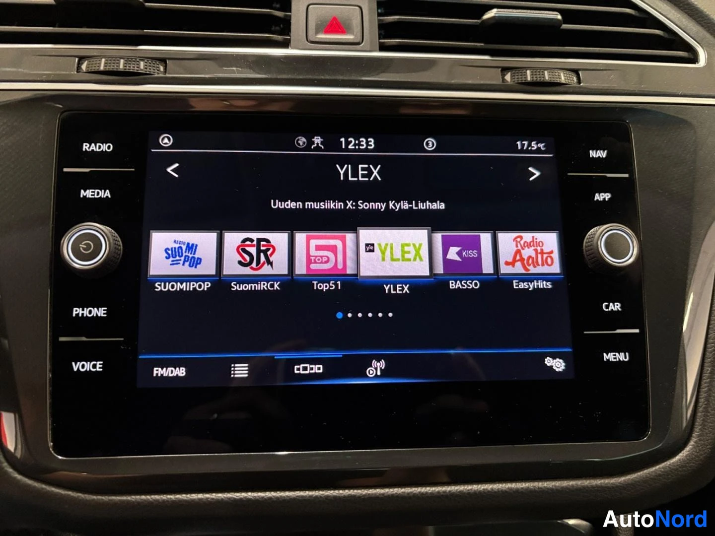 Yksityiskohta: Volkswagenin infotainment-näyttö radionäkymässä YLEX-kanava valittuna, kello 12:33 ja lämpötila 17,5 °C.