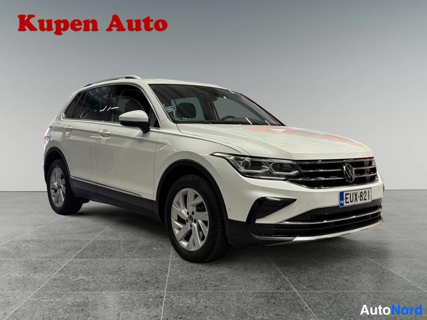 Etuviisto, nokka oikealle: Valkoinen Volkswagen Tiguan -maastokulkuajoneuvo kuvattu kolmanneskulmasta edestä oikealta, rekisteritunnus.