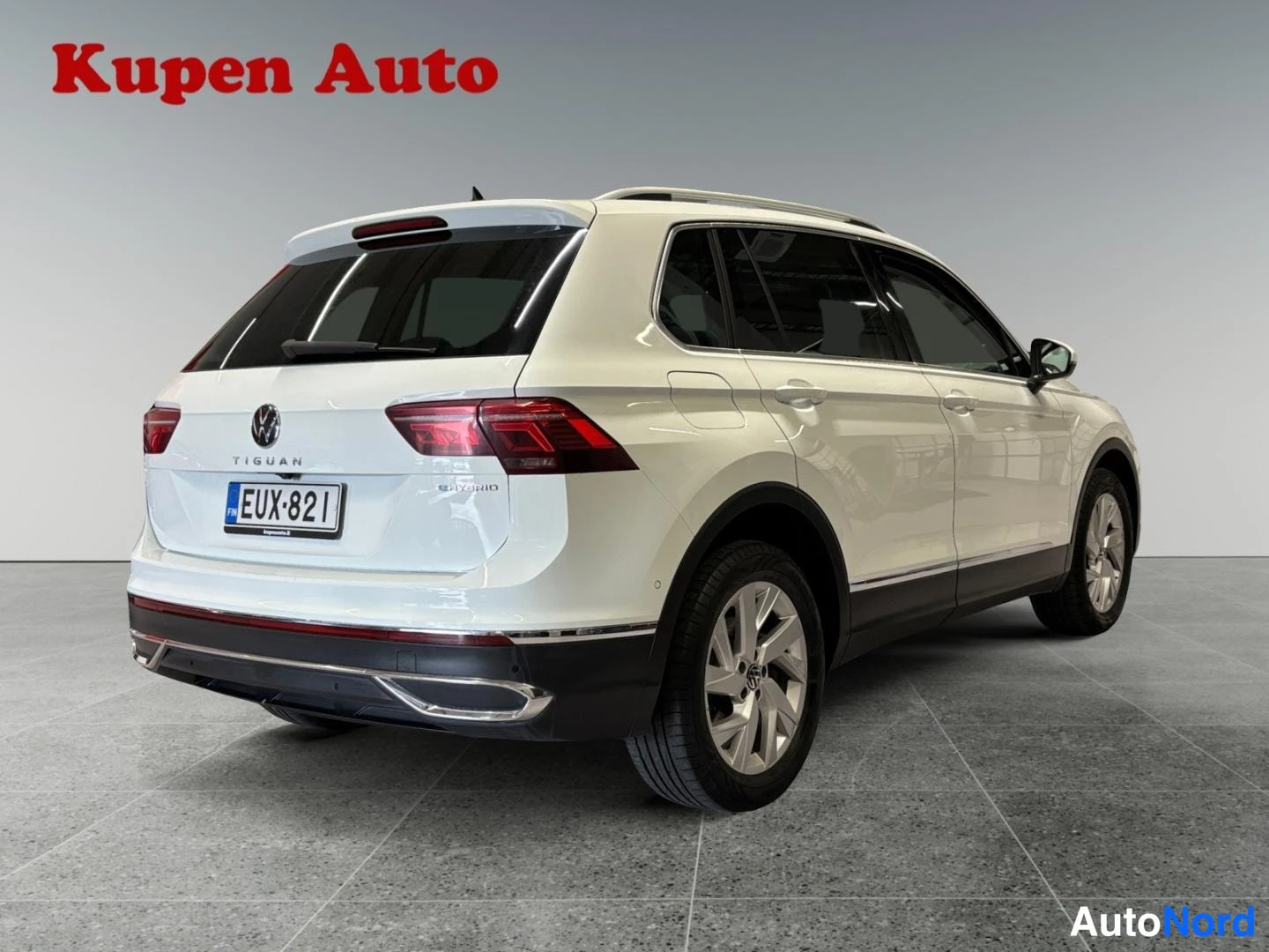 Takaviisto: Valkoinen Volkswagen Tiguan kuvattu takakulmasta vasemmalta, rekisteritunnus, perän TIGUAN-teksti näkyy.