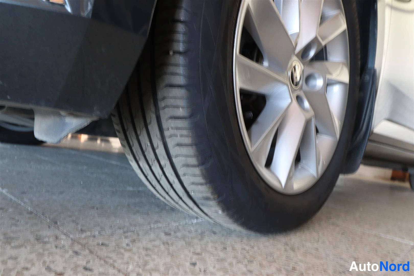 Yksityiskohta: Lähikuva autovaran pyörästä ja hopeisesta vanteesta autotallin lattialla