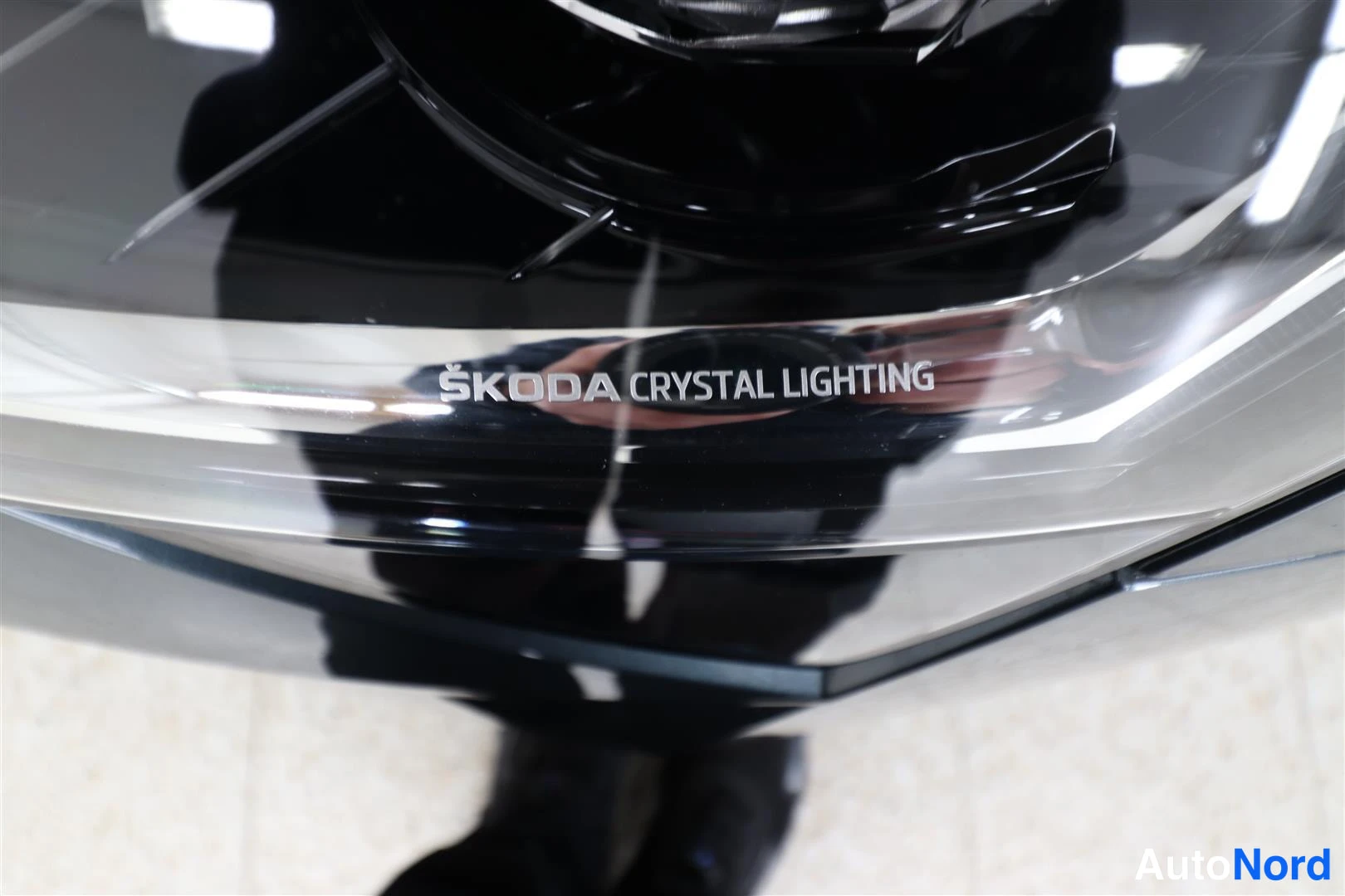 Edestä: Lähikuva auton etumerkistä, jossa lukee ŠKODA CRYSTAL LIGHTING.