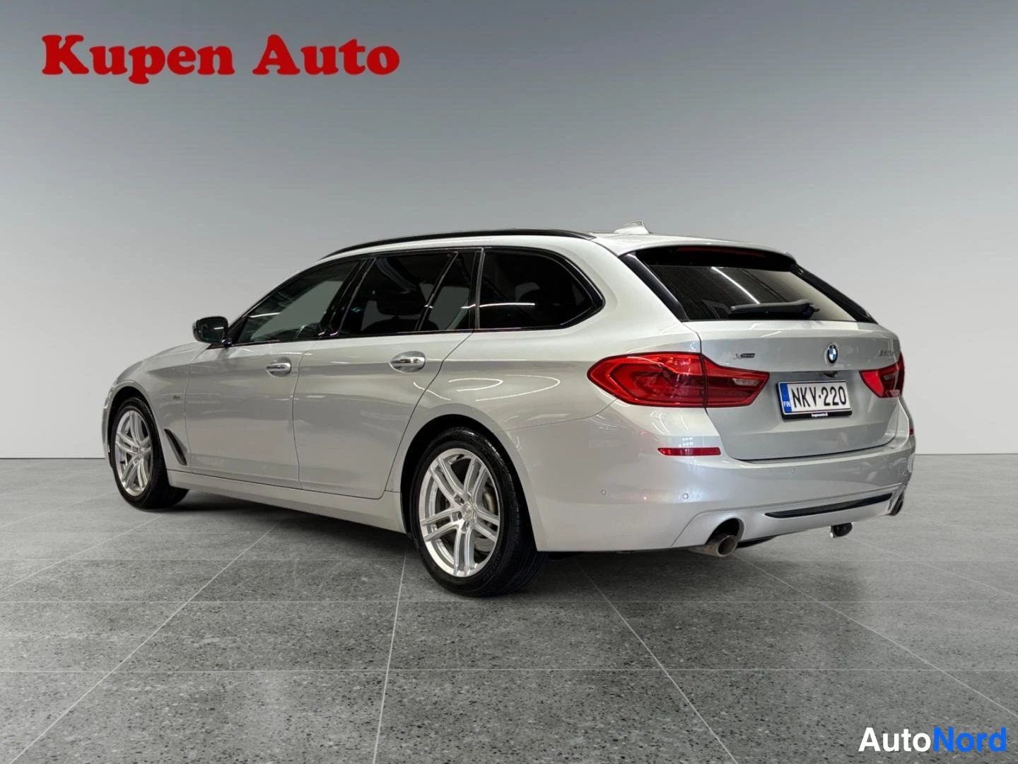 Takaviisto: Hopeanharmaa BMW 520d Touring -farmari kolmanneltapyöristä takaa oikealle, takavalot ja -kilpi.