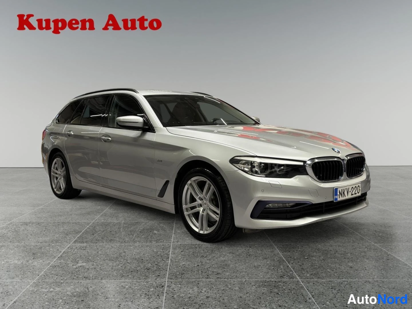 Etuviisto, nokka oikealle: Hopeanharmaa BMW 520d Touring -farmari kolmanneltapyöristä edusta oikealle, etusäleikkö ja -kilpi.
