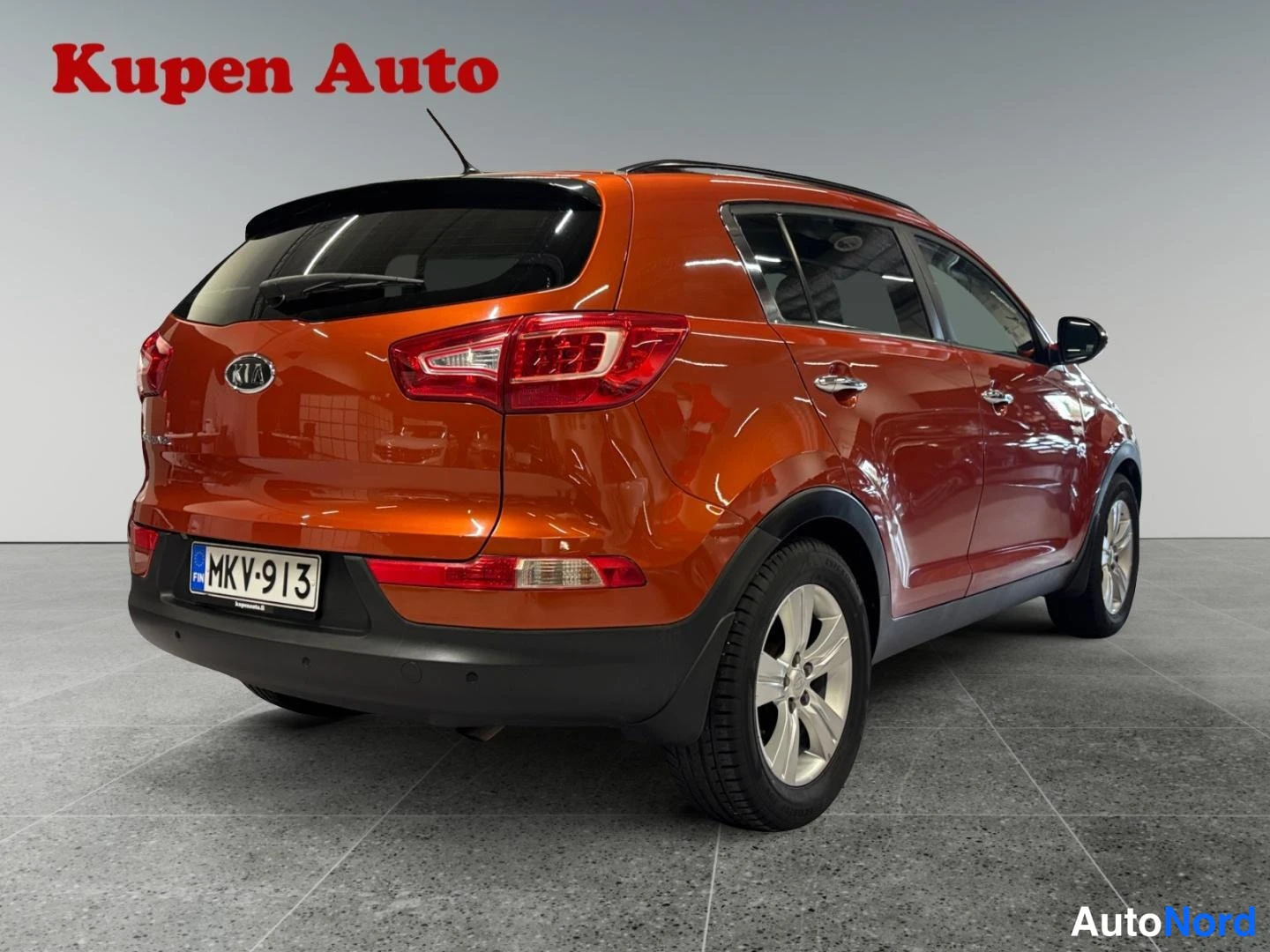 Takaviisto: Kia Sportage takaa vasemmalta kolmiväripisteenä; kylkiluomivalot ja rekisterikilpi näkyvissä.