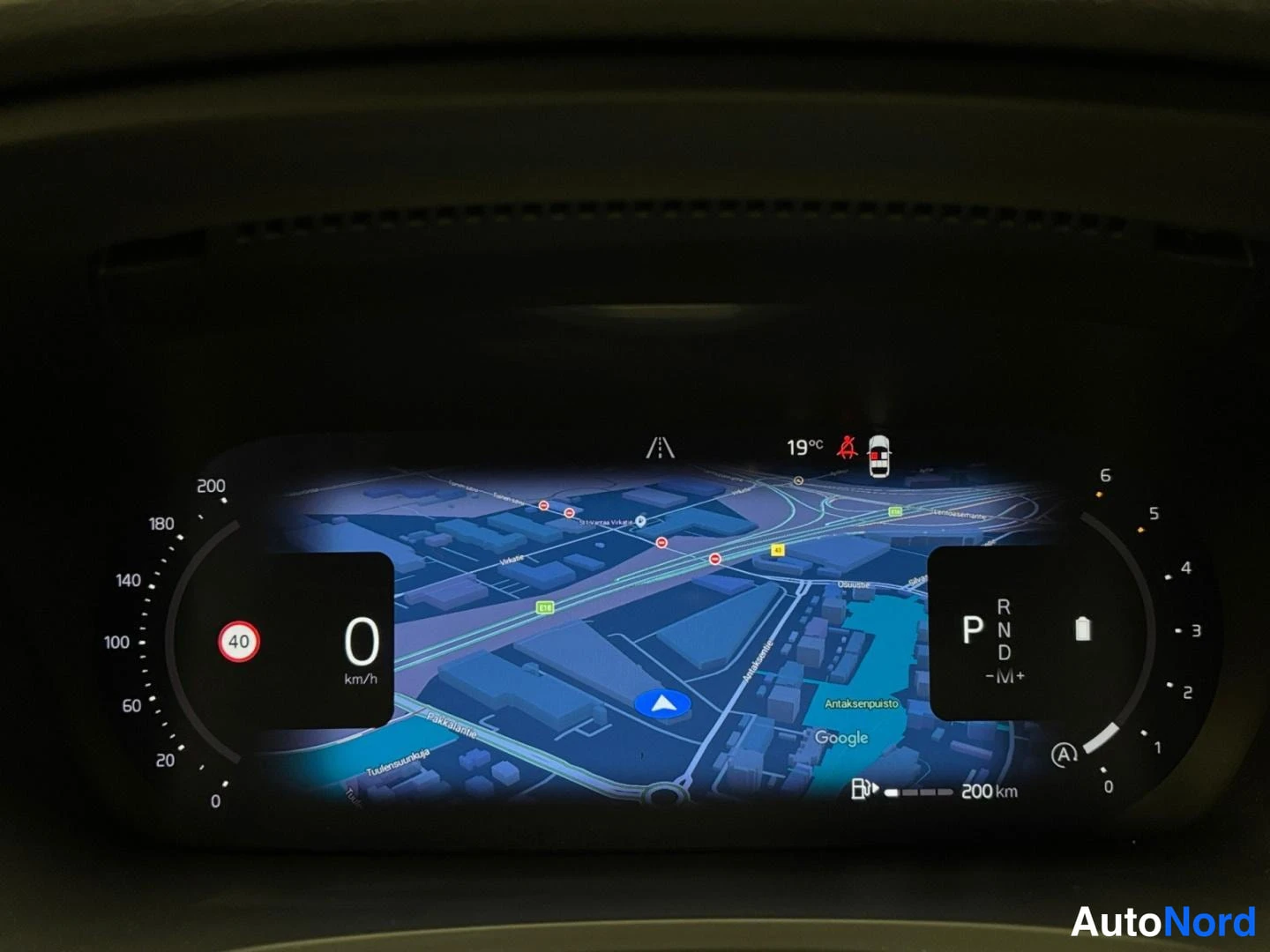 Muu: Volvo V90:n digitaalinen kuljettajanäyttö: nopeus 0 km/h, vaihde P, karttanavigointi, ulkolämpötila 19 °C, kaistavahti- ja ajoneuvotunnistuksen symbolit, toimin