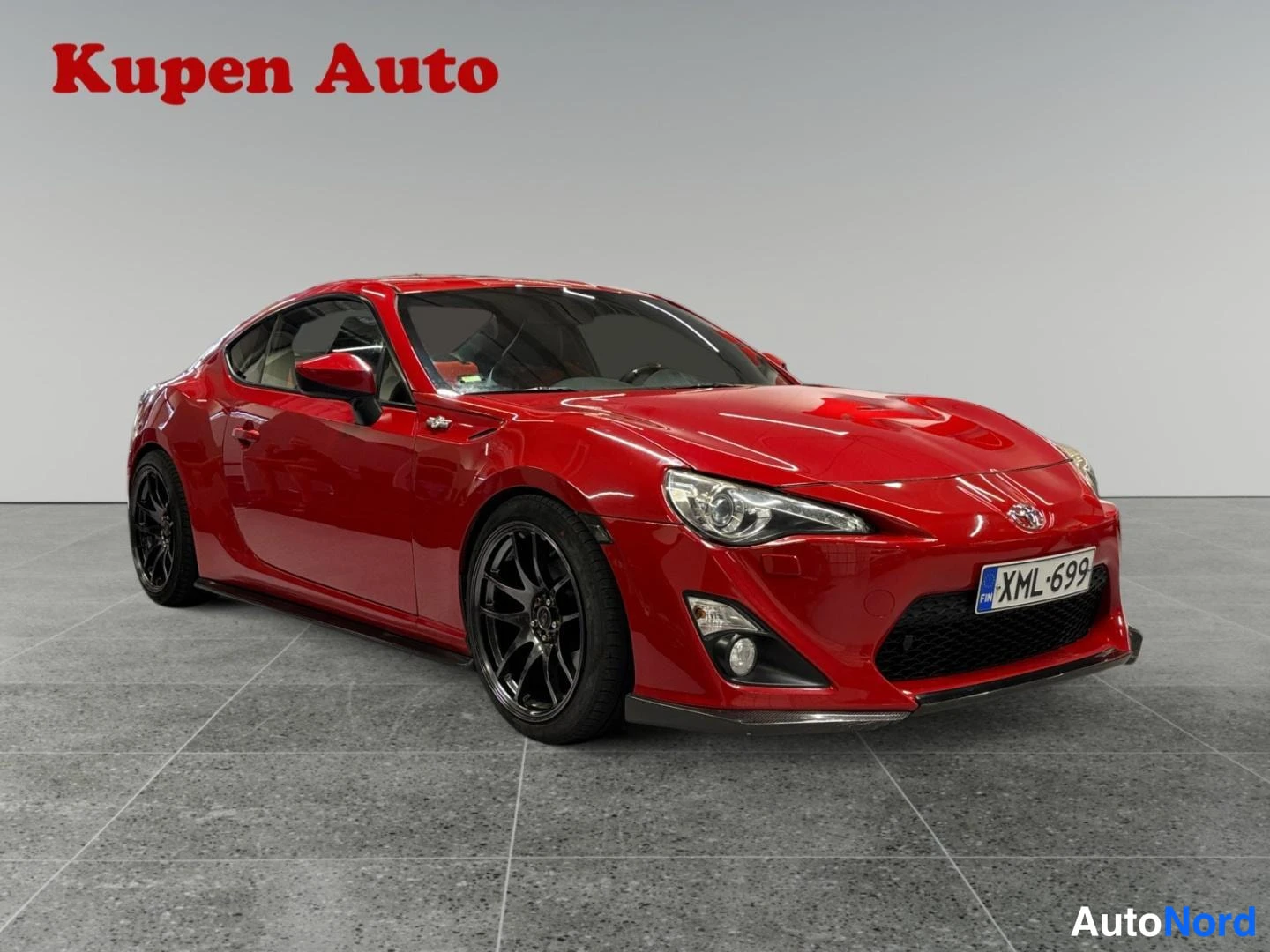 Etuviisto, nokka oikealle: Punaisen Toyota GT86:n etukolmasonäkö oikealta, tummat kevytmetallivanteet, rekisteri, studiossa.