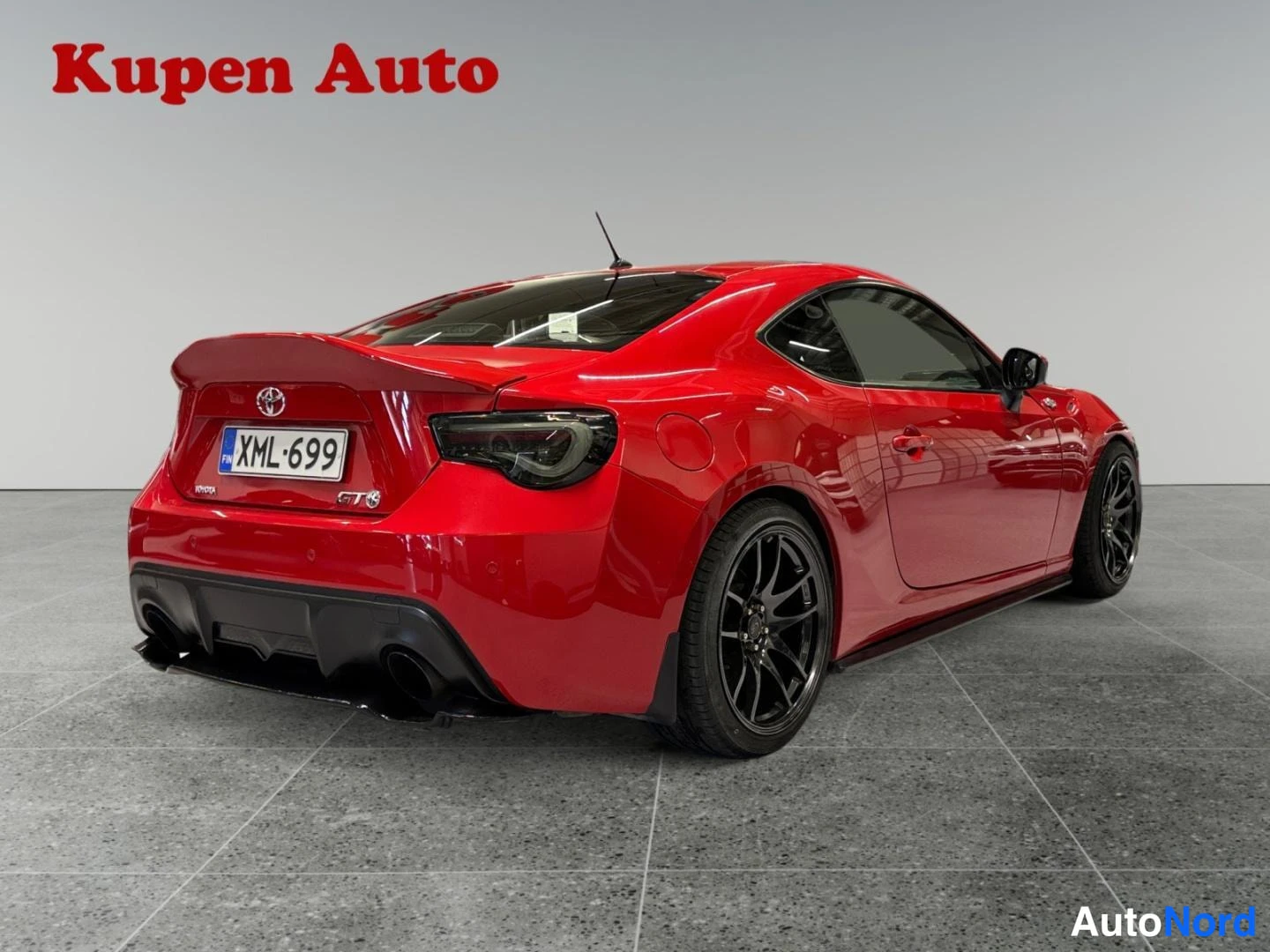 Takaviisto: Punaisen Toyota GT86:n takakolmasonäkö oikealta, tummat vanteet, kaksoispakoputket ja rekisteri.
