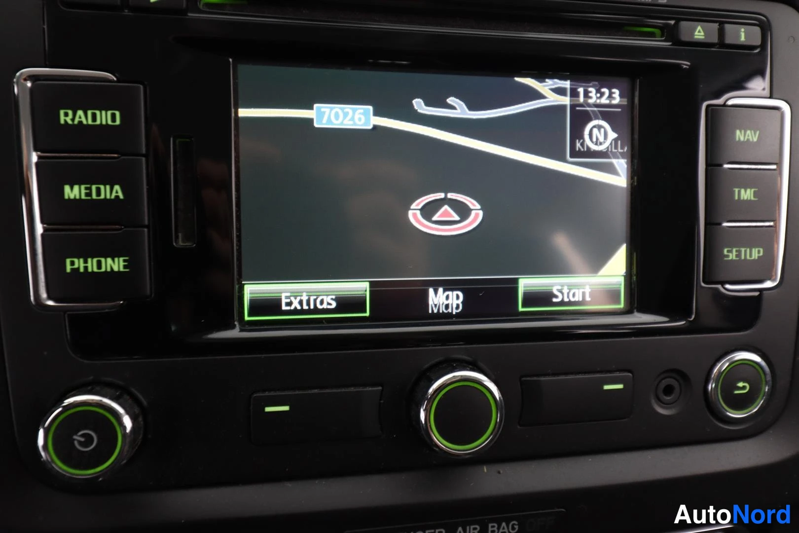 Yksityiskohta: Autoradion ja navigaattorin näyttö, jossa karttanäkymä ja painikkeet Radio, Media, Phone, Nav, TMC ja Setup.