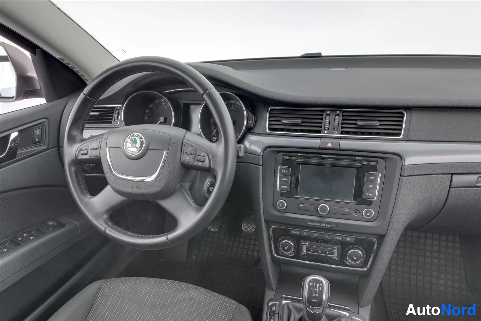 Muu: Lähikuva ohjaamosta: Skoda-merkitty ohjauspyörä, mittaristo, radioviritin ja automaattivaihteen valitsin.