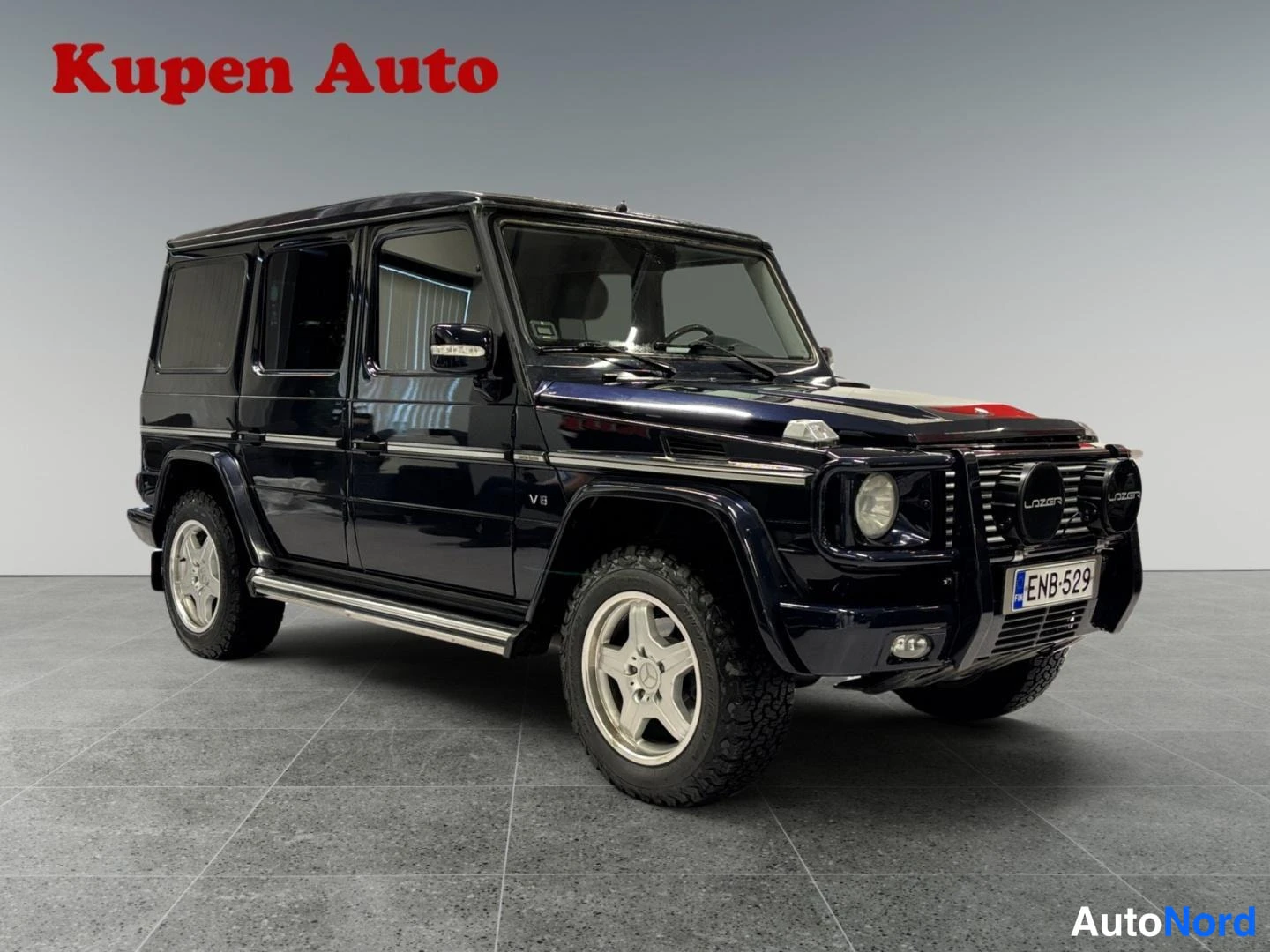 Etuviisto, nokka oikealle: Mercedes-Benz G -farmari etualalta oikealta kuvattuna, tummansininen