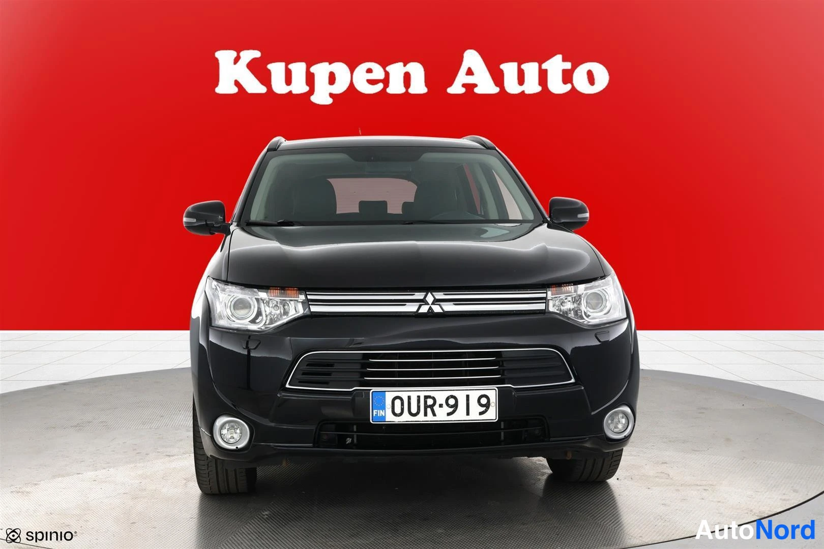 Edestä: Mustan Mitsubishi Outlanderin etupää rekisterikilvellä punaisella taustalla.