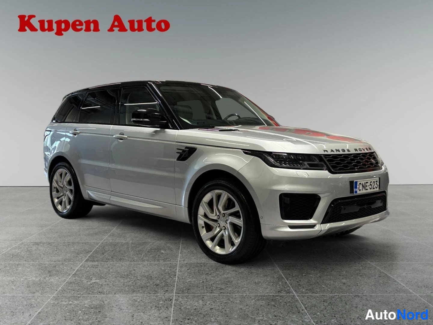 Etuviisto, nokka oikealle: Hopeanvärinen Range Rover Sport etukulmasta oikealta, rekisterikilpi, musta katto.