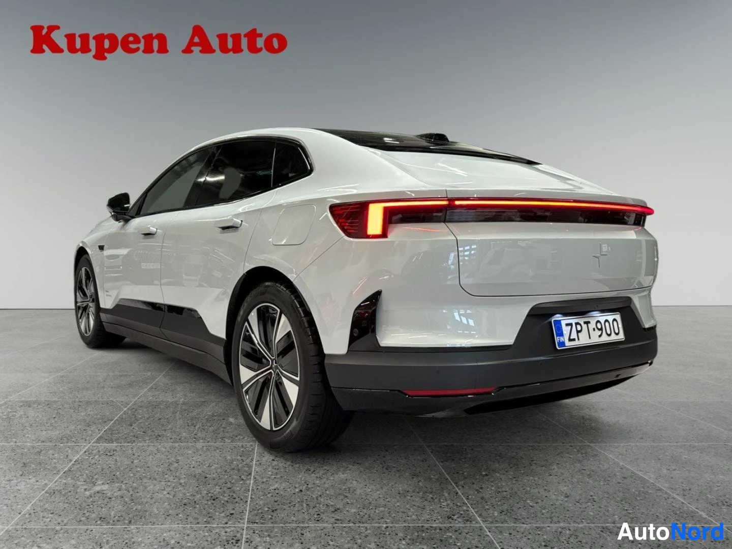 Takaviisto: Auton takakolmannelänsäkuva, valkoinen coupé-korinen auto, koko leveydeltään punainen takavalo ja rekisterikilpi.