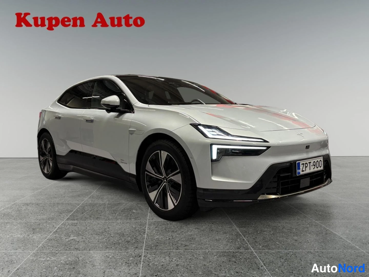 Etuviisto, nokka oikealle: Auton etukolmannelänsäkuva keulasta oikealle, valkoinen coupe-tyyppinen sähköauto studiossa, rekisterikilpi.
