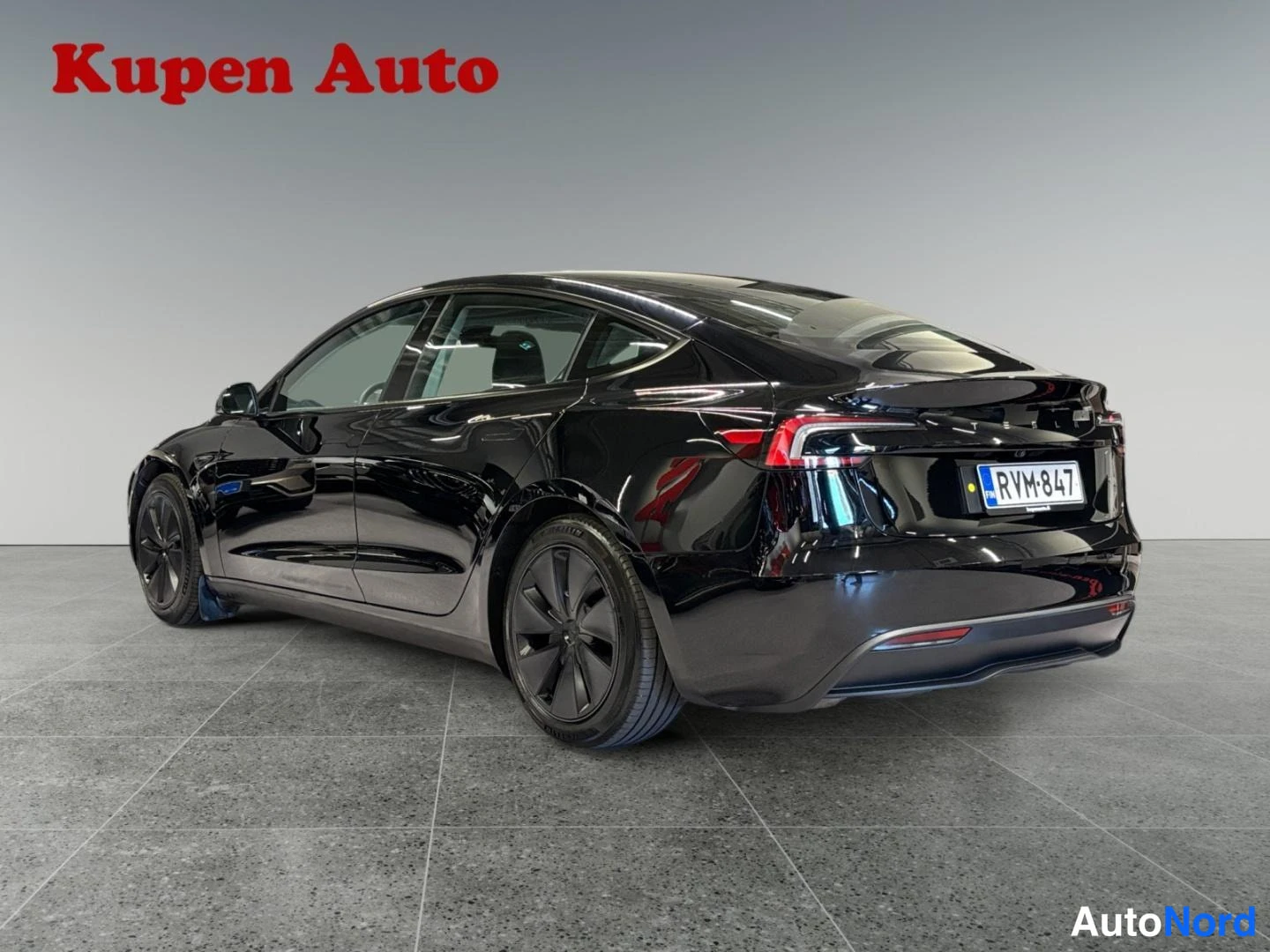 Takaviisto: Musta Tesla Model 3 -henkilöauto takaviistosta sisätiloissa, rekisteritunnus.