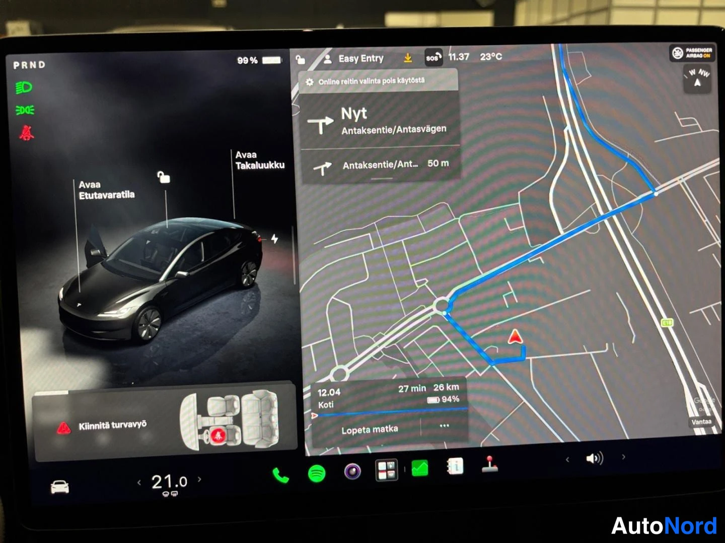 Muu: Tesla Model 3:n keskityynyt näyttää navigointikarttaa reitillä Antaksentie/Antaksvägen sekä ajoneuvon tilanäkymää, jossa lukee 'Avaa Etuvarastila' ja 'Avaa Taka