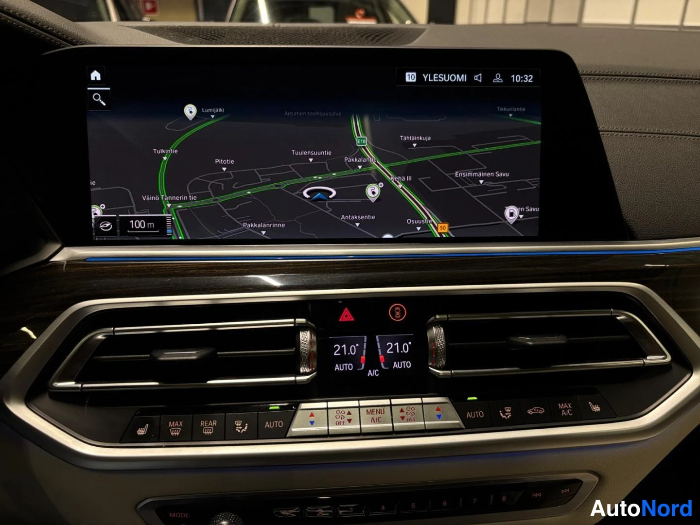 Muu: Lähikuva infotainment-näytöstä ja ilmastoinnin hallintapaneelista; näytössä YLESUOMI-kartta ja kello 10:32, paneelissa 21,0° AUTO A/C ja lämmityspainikkeet.