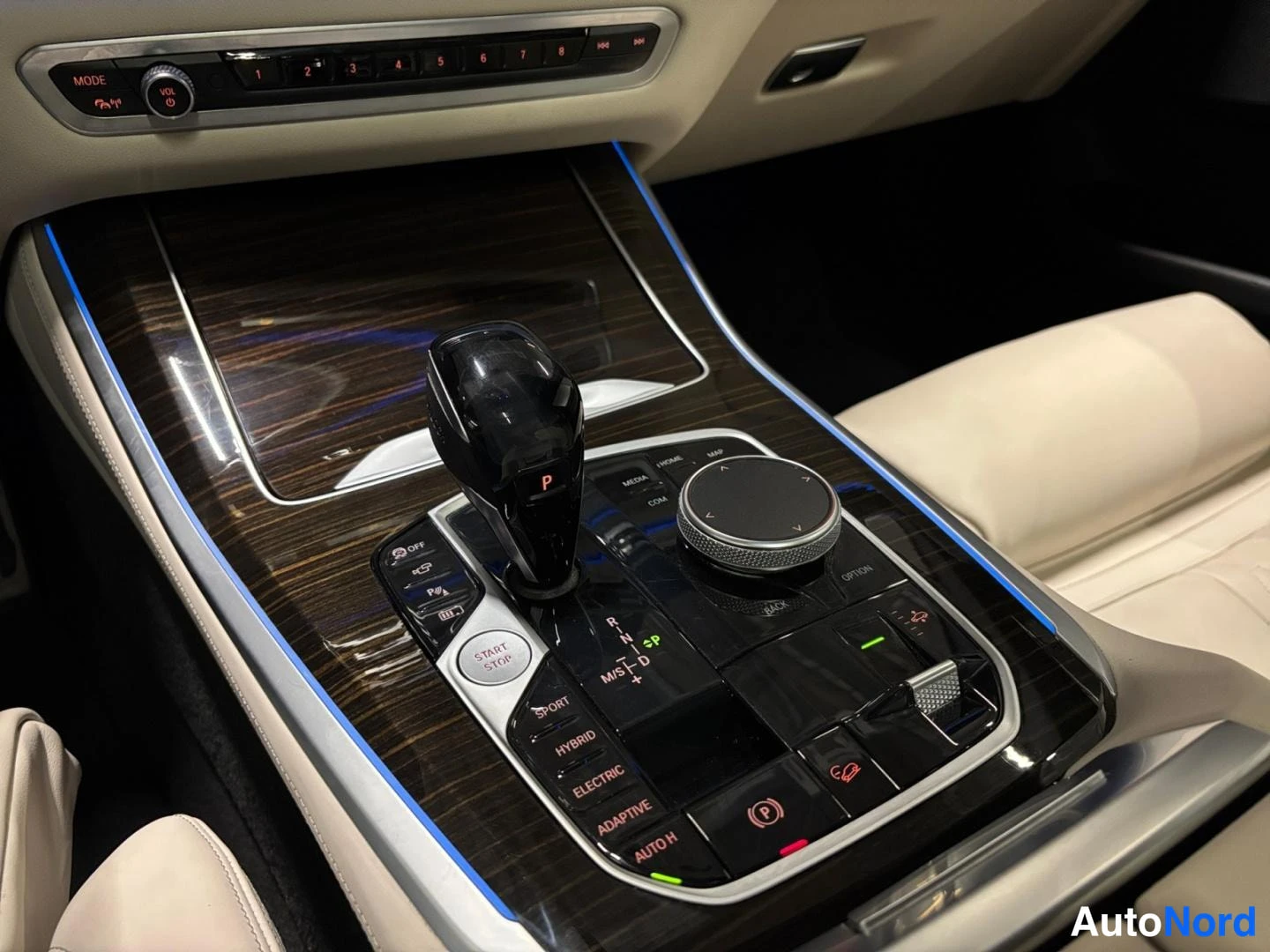 Muu: Auton keskikonsolin kuva: vaihteenvalitsin, iDrive-säädin ja napit kuten SPORT, HYBRID, ELECTRIC ja ADAPTIVE.