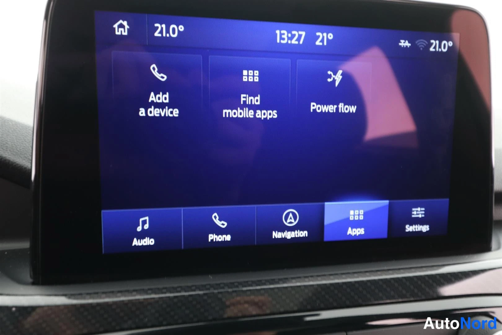 Muu: Auton kosketusnäytön aloitusnäkymä: yläpalkissa 13:27 ja 21°, valikossa Add a device, Find mobile apps ja Power flow, alareunassa palkit Audio, Phone, Navigatio