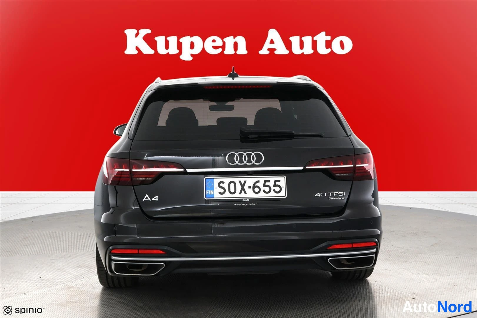 Takaa: Musta farmariauto suoraan takaa kuvattuna; peräovat, Audi-merkki, rekisterikilpi S0X-655 ja kaksoset pakoputket näkyvät punaista taustaa vasten.