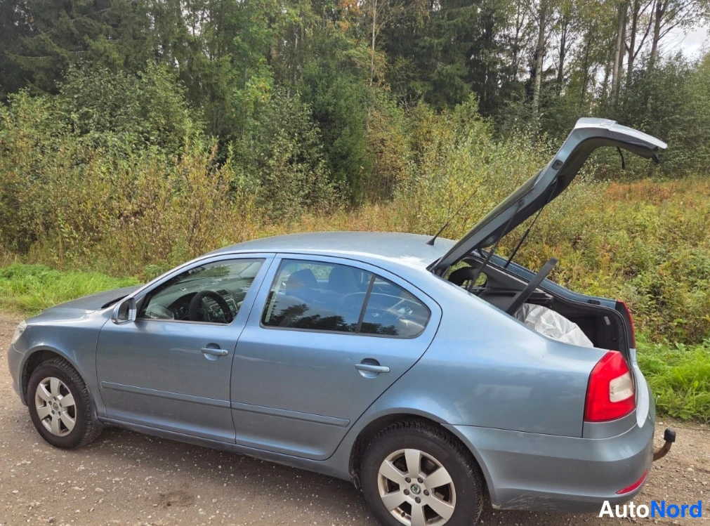 Takaviisto: Sinertävän harmaan auton sivusta ja takaosasta otettu kuva, avattu tavaratilan kansi auki.