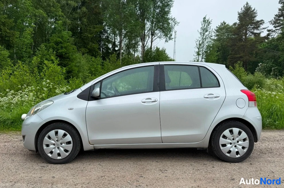 Sivulta: Sivukuvatä hopeanvärisestä Toyota Yaris -viistoperästä nurmikkoaukean reunalla.