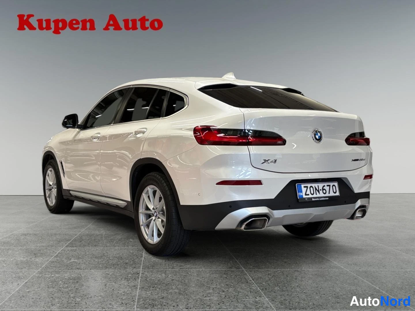 Takaviisto: BMW X4, valkoinen, takakulmakuva vasemmalta, rekisteritunnus, showroom-lattialla